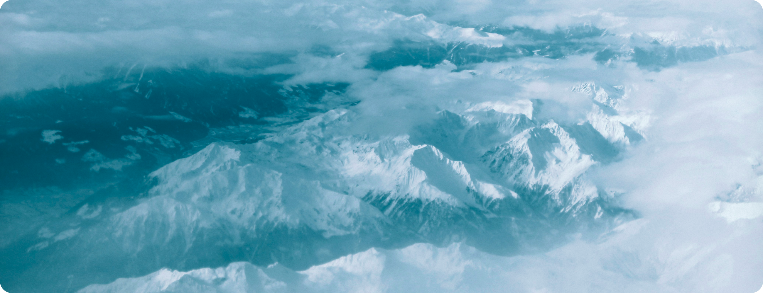 雲の間から見える雪を被った山脈の景色